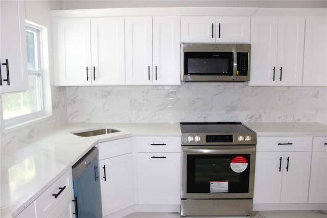 1109 N Obrien St, Tampa, FL 33607 - kitchen featuring appliances with stainless steel finishes, white cabinetry, tasteful backsplash, and light stone countertops