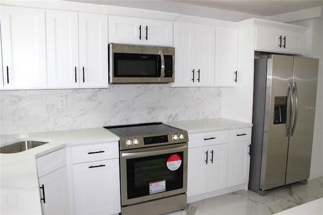 1109 N Obrien St, Tampa, FL 33607 - kitchen featuring stainless steel appliances, white cabinets, light marble finish floors, and tasteful backsplash