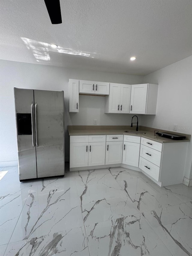 1109 N Obrien St, Tampa, FL 33607 - kitchen featuring stainless steel fridge with ice dispenser, a sink, white cabinets, light marble finish flooring, and a textured ceiling