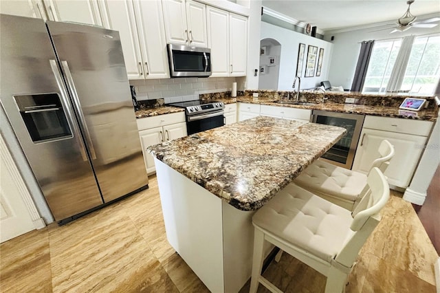1842 Ridgelake Ct, Wesley Chapel, FL 33543 - kitchen featuring stainless steel appliances, a sink, arched walkways, ornamental molding, and stone counters