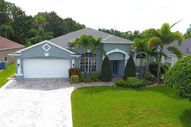 1842 Ridgelake Ct, Wesley Chapel, FL 33543 - view of front facade with a front yard, a garage, decorative driveway, stucco siding, and central AC