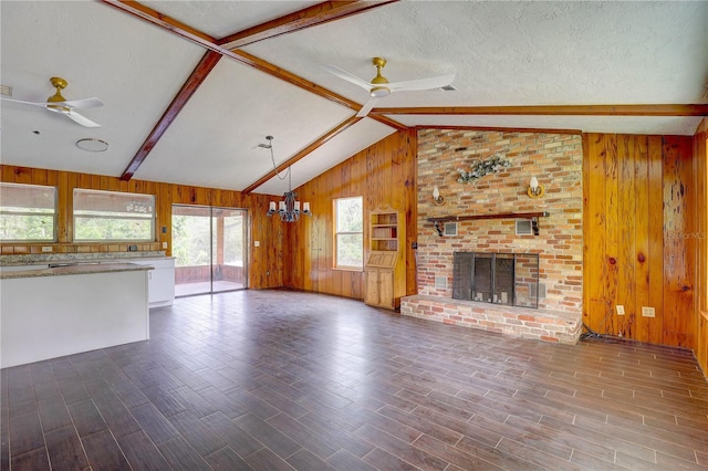 5290 Cyril Dr, Dade City, FL 33523 - unfurnished living room with a ceiling fan, wooden walls, a brick fireplace, a chandelier, and dark wood finished floors