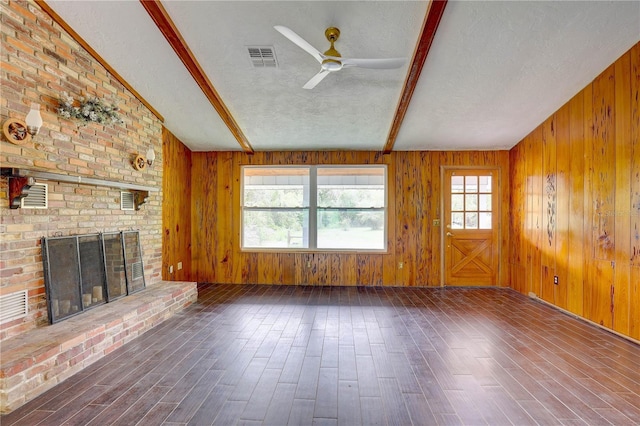 5290 Cyril Dr, Dade City, FL 33523 - unfurnished living room with a textured ceiling, wood finished floors, a ceiling fan, a fireplace, and wood walls