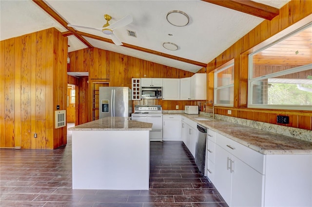 5290 Cyril Dr, Dade City, FL 33523 - kitchen with stainless steel appliances, lofted ceiling, wooden walls, a center island, and white cabinetry