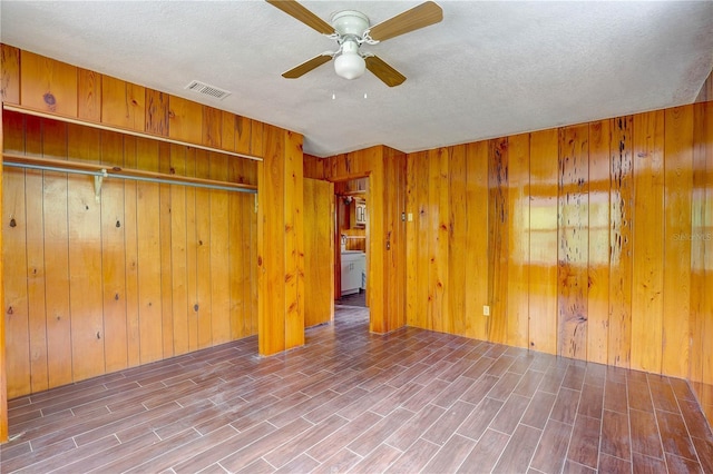 5290 Cyril Dr, Dade City, FL 33523 - unfurnished bedroom featuring wood finished floors, wooden walls, a textured ceiling, a ceiling fan, and a closet