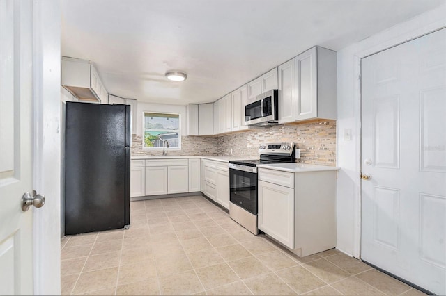 3008 E Wilder Ave, Tampa, FL 33610 - kitchen featuring appliances with stainless steel finishes, light countertops, decorative backsplash, light tile patterned floors, and white cabinetry
