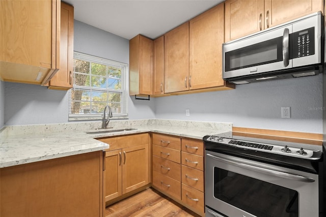 2809 Marconi St, Tampa, FL 33605 - kitchen featuring stainless steel appliances, a sink, light wood-style floors, light stone counters, and brown cabinetry