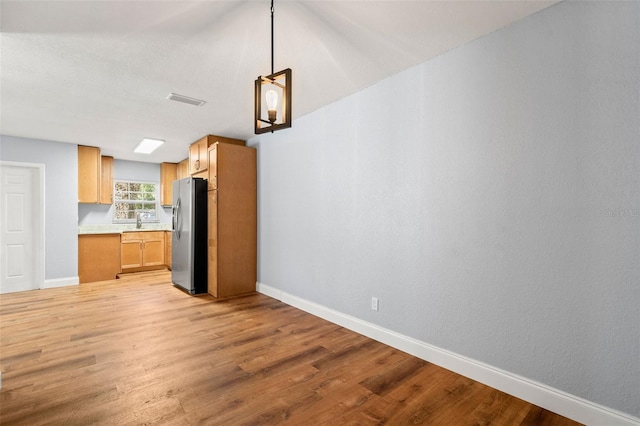 2809 Marconi St, Tampa, FL 33605 - kitchen with stainless steel fridge with ice dispenser, light countertops, light wood finished floors, baseboards, and a sink