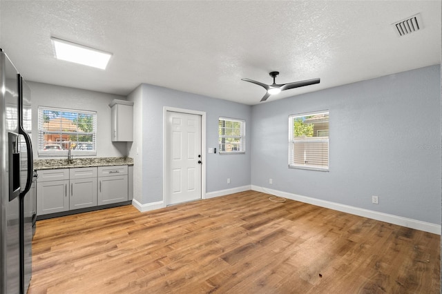 2809 Marconi St, Tampa, FL 33605 - kitchen featuring refrigerator with ice dispenser, light wood-style flooring, a textured ceiling, baseboards, and light stone countertops