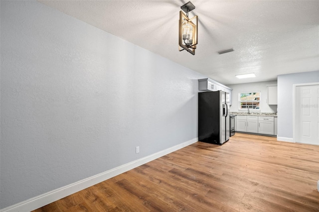 2809 Marconi St, Tampa, FL 33605 - kitchen featuring refrigerator with ice dispenser, baseboards, light wood finished floors, a textured ceiling, and a textured wall