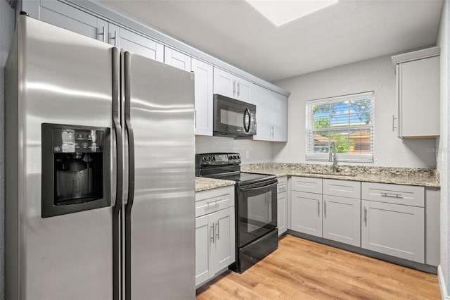 2809 Marconi St, Tampa, FL 33605 - kitchen with black appliances, a sink, light wood finished floors, and light stone counters