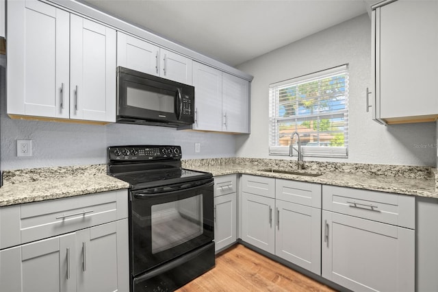2809 Marconi St, Tampa, FL 33605 - kitchen featuring black appliances, a sink, light wood-style floors, light stone counters, and a textured wall