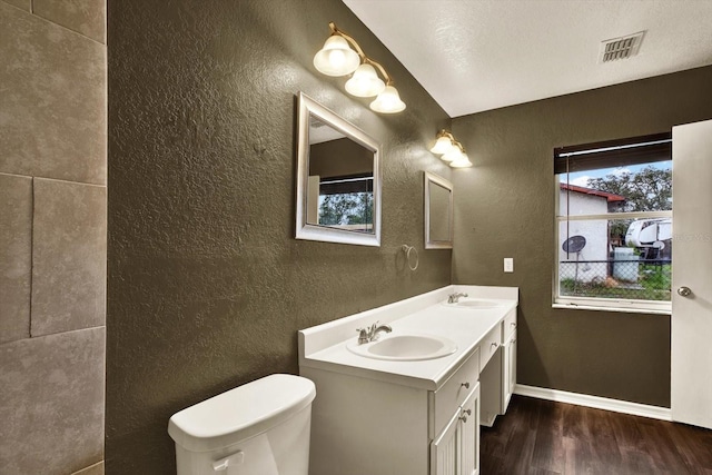 4342 Candler Ave, Spring Hill, FL 34609 - bathroom featuring a textured wall, wood finished floors, double vanity, toilet, and baseboards
