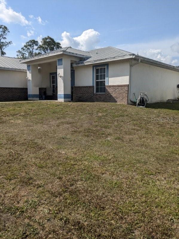 9761 Councilor Ln, North Fort Myers, FL 33917 - view of side of property featuring brick siding, stucco siding, and a yard