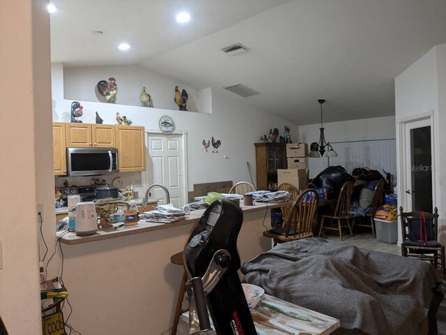 9761 Councilor Ln, North Fort Myers, FL 33917 - kitchen with stainless steel microwave, lofted ceiling, a kitchen breakfast bar, light brown cabinets, and a sink