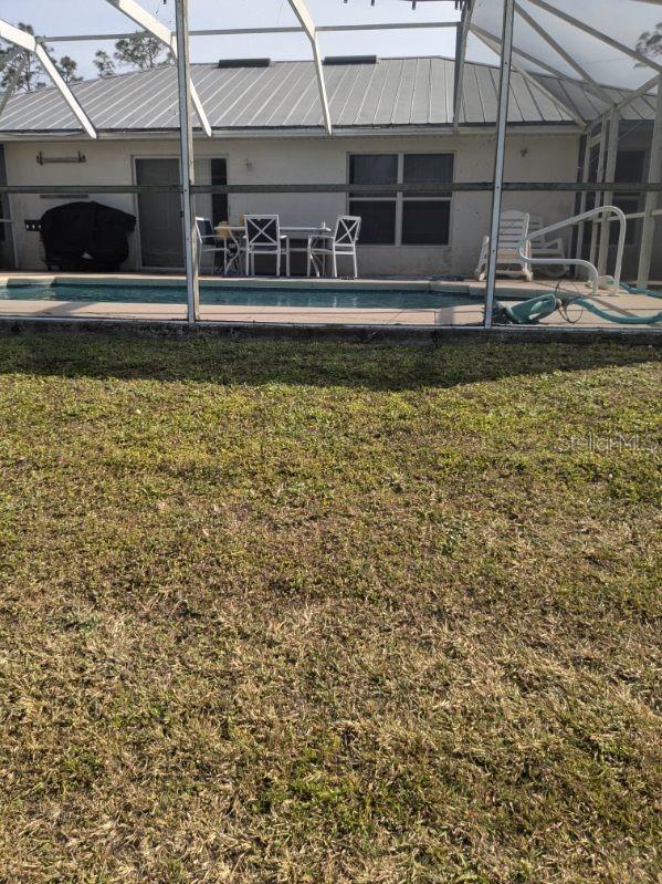 9761 Councilor Ln, North Fort Myers, FL 33917 - back of property featuring glass enclosure, a yard, and an outdoor pool