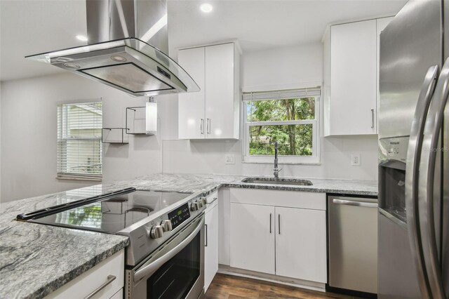 1311 W Perdiz St, Tampa, FL 33612 - kitchen with appliances with stainless steel finishes, range hood, white cabinets, light stone counters, and dark wood-style floors