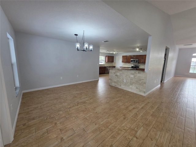 13551 Banner Rd, Spring Hill, FL 34609 - unfurnished living room featuring a chandelier, light wood-type flooring, and baseboards