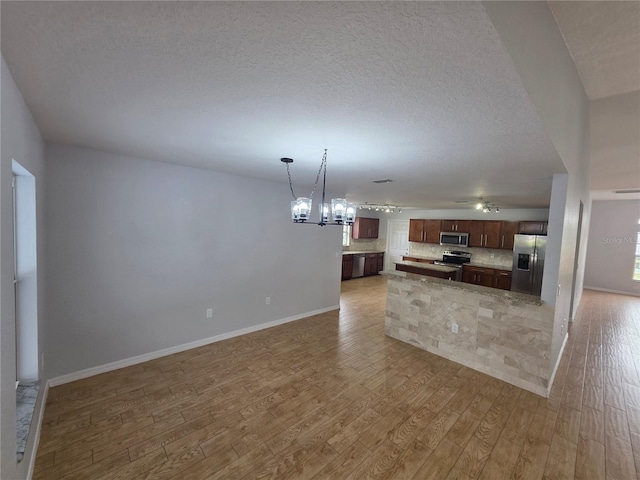 13551 Banner Rd, Spring Hill, FL 34609 - kitchen with appliances with stainless steel finishes, open floor plan, light wood-style floors, backsplash, and a textured ceiling