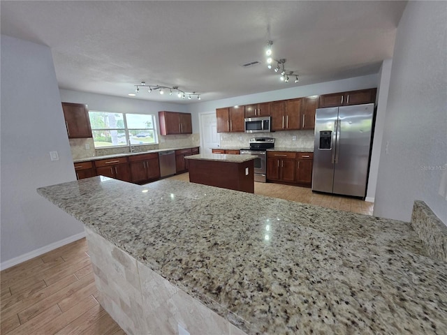 13551 Banner Rd, Spring Hill, FL 34609 - kitchen featuring stainless steel appliances, backsplash, a center island, and light wood finished floors