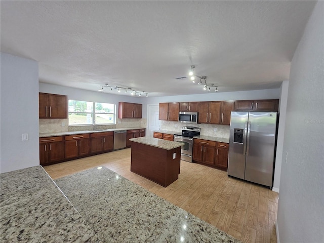 13551 Banner Rd, Spring Hill, FL 34609 - kitchen featuring stainless steel appliances, a sink, tasteful backsplash, light wood-type flooring, and a kitchen island