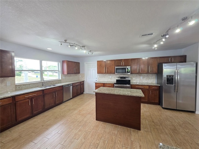 13551 Banner Rd, Spring Hill, FL 34609 - kitchen featuring appliances with stainless steel finishes, light wood-style flooring, track lighting, backsplash, and a textured ceiling