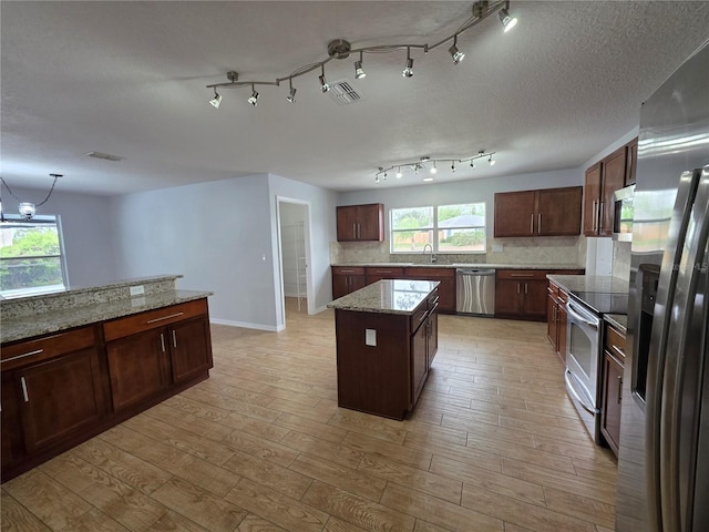 13551 Banner Rd, Spring Hill, FL 34609 - kitchen featuring appliances with stainless steel finishes, light wood-style flooring, tasteful backsplash, and a center island