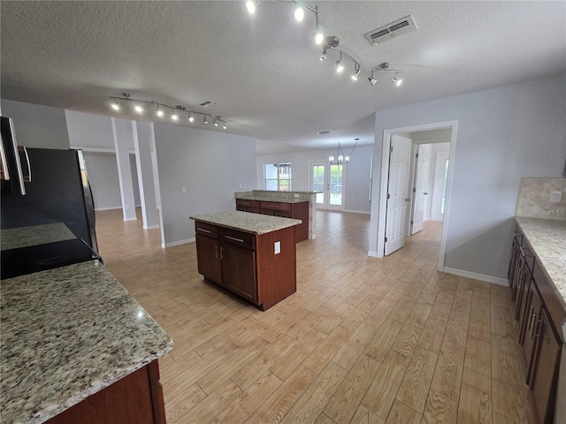13551 Banner Rd, Spring Hill, FL 34609 - kitchen featuring a center island, a textured ceiling, baseboards, freestanding refrigerator, and light wood finished floors