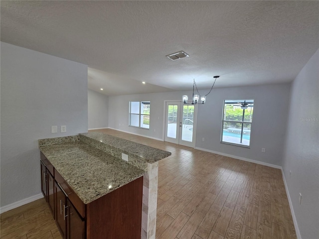 13551 Banner Rd, Spring Hill, FL 34609 - kitchen with light wood-style floors, baseboards, plenty of natural light, a peninsula, and a textured ceiling