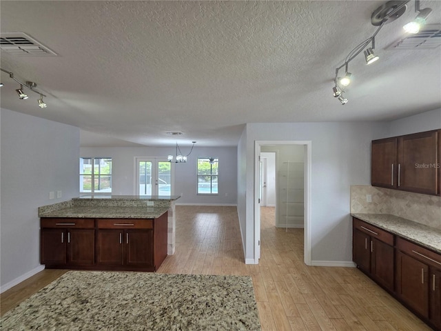 13551 Banner Rd, Spring Hill, FL 34609 - kitchen with rail lighting, baseboards, light wood-style floors, a textured ceiling, and plenty of natural light