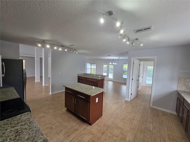 13551 Banner Rd, Spring Hill, FL 34609 - kitchen with freestanding refrigerator, a kitchen island, baseboards, track lighting, and light wood-style flooring