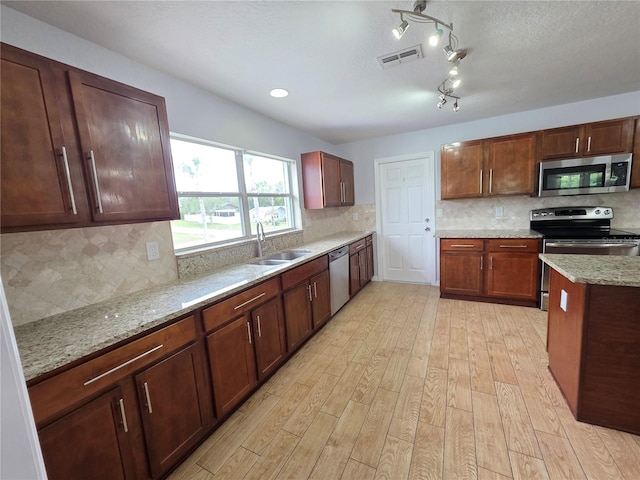 13551 Banner Rd, Spring Hill, FL 34609 - kitchen featuring appliances with stainless steel finishes, a sink, light wood-style flooring, decorative backsplash, and light stone countertops