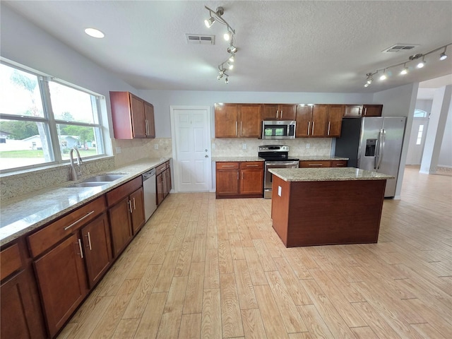 13551 Banner Rd, Spring Hill, FL 34609 - kitchen featuring stainless steel appliances, a sink, a kitchen island, light wood-style floors, and rail lighting