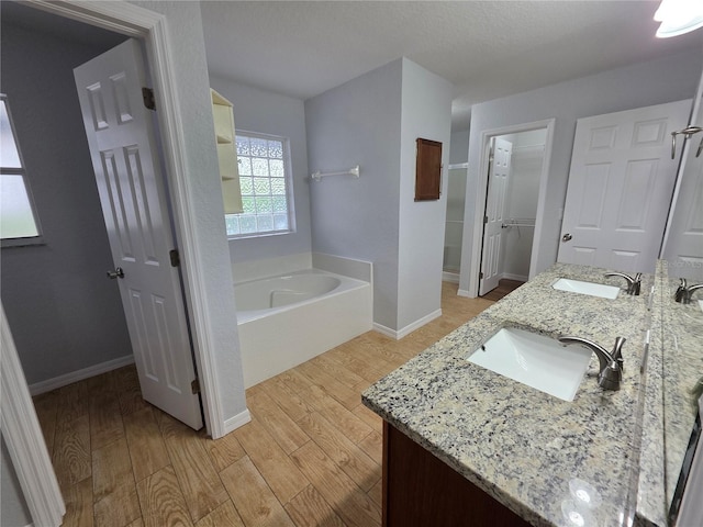 13551 Banner Rd, Spring Hill, FL 34609 - bathroom with wood finished floors, a bath, double vanity, baseboards, and a closet