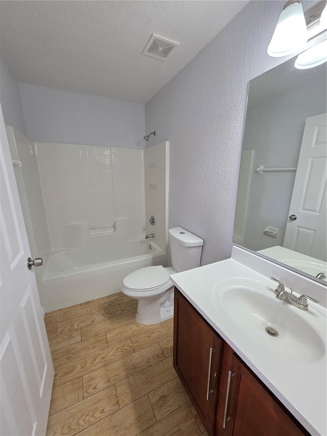 13551 Banner Rd, Spring Hill, FL 34609 - full bath featuring wood finished floors, vanity, toilet, shower / washtub combination, and a textured wall