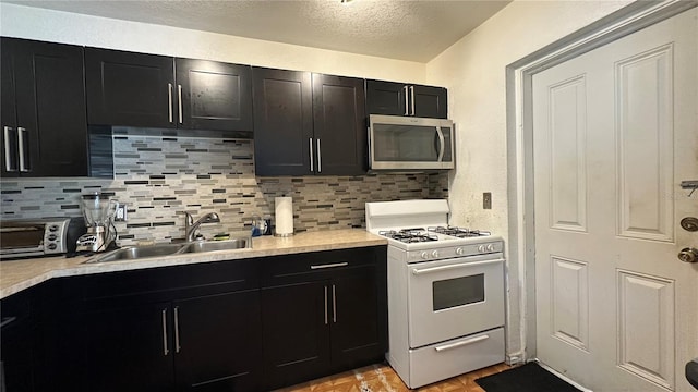 1701 NW 10th Ave, Fort Lauderdale, FL 33311 - kitchen featuring stainless steel microwave, gas range gas stove, a sink, dark cabinetry, and a textured ceiling