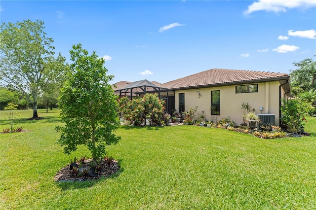 137 Silver Falls Dr, Apollo Beach, FL 33572 - back of house with a yard, a tile roof, stucco siding, glass enclosure, and central AC