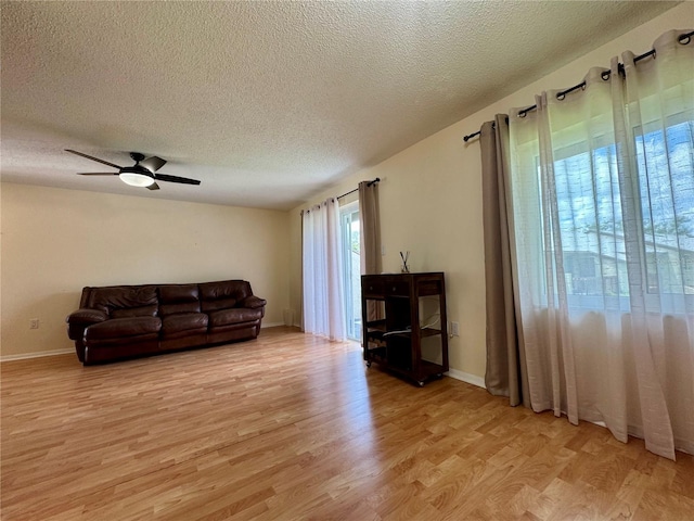 4215 E Bay Dr Unit 1707C, Clearwater, FL 33764 - living area featuring light wood-style floors, a textured ceiling, a ceiling fan, and baseboards
