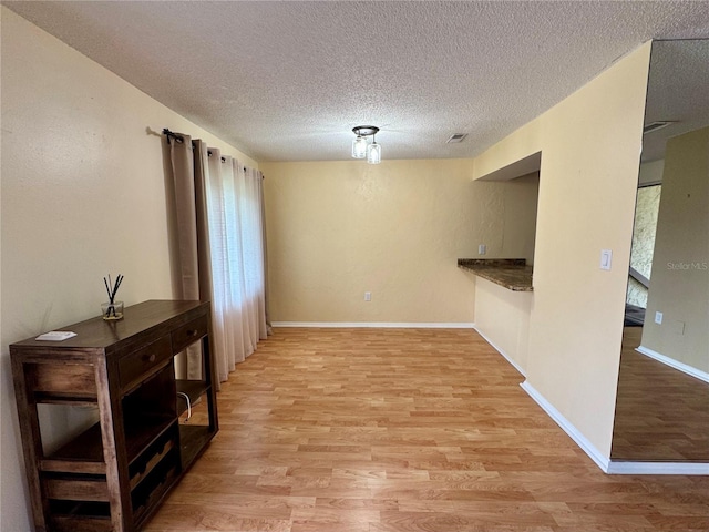 4215 E Bay Dr Unit 1707C, Clearwater, FL 33764 - unfurnished dining area featuring light wood-type flooring, a textured ceiling, and baseboards