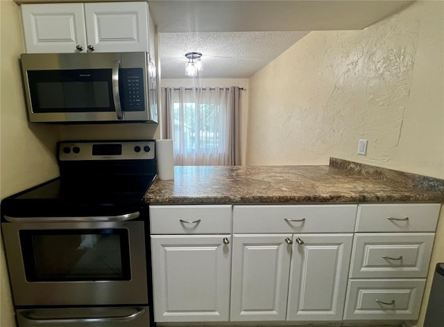 4215 E Bay Dr Unit 1707C, Clearwater, FL 33764 - kitchen with stainless steel appliances, a textured ceiling, dark countertops, a textured wall, and white cabinets