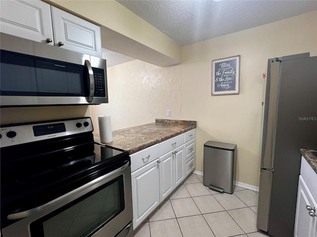 4215 E Bay Dr Unit 1707C, Clearwater, FL 33764 - kitchen with stainless steel appliances, a textured ceiling, white cabinets, dark countertops, and light tile patterned flooring