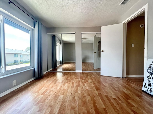 4215 E Bay Dr Unit 1707C, Clearwater, FL 33764 - unfurnished bedroom featuring multiple closets, light wood-style flooring, a textured ceiling, and baseboards