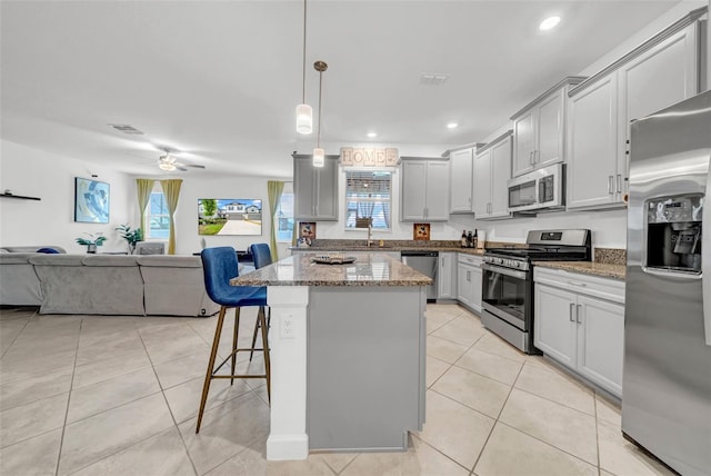 3216 Bryant Park Dr, New Port Richey, FL 34655 - kitchen with appliances with stainless steel finishes, open floor plan, light tile patterned flooring, a breakfast bar area, and light stone countertops