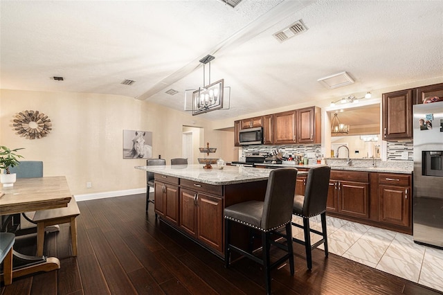 9220 Mcintosh Rd, Dover, FL 33527 - kitchen with appliances with stainless steel finishes, a breakfast bar, vaulted ceiling, a chandelier, and tasteful backsplash