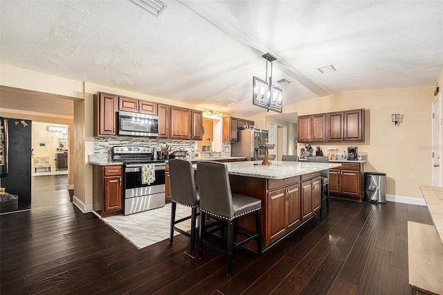 9220 Mcintosh Rd, Dover, FL 33527 - kitchen featuring appliances with stainless steel finishes, wood finished floors, a center island, a kitchen bar, and pendant lighting