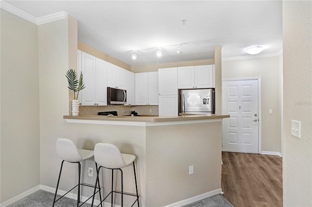 4221 W Spruce St Unit 1429, Tampa, FL 33607 - kitchen featuring appliances with stainless steel finishes, a kitchen breakfast bar, baseboards, white cabinets, and ornamental molding