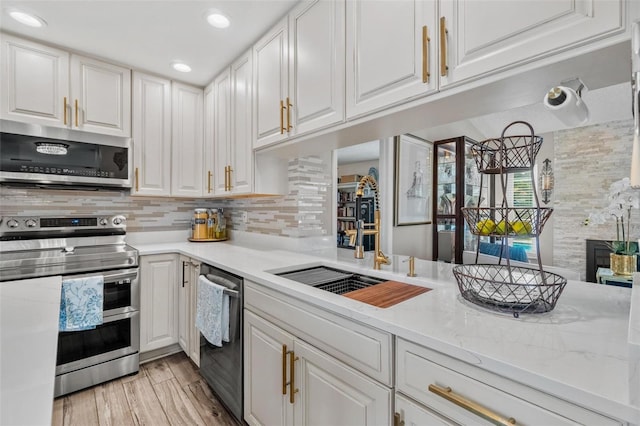 2824 Paddock Dr, Palm Harbor, FL 34684 - kitchen featuring stainless steel appliances, white cabinetry, tasteful backsplash, light wood-style floors, and light stone countertops
