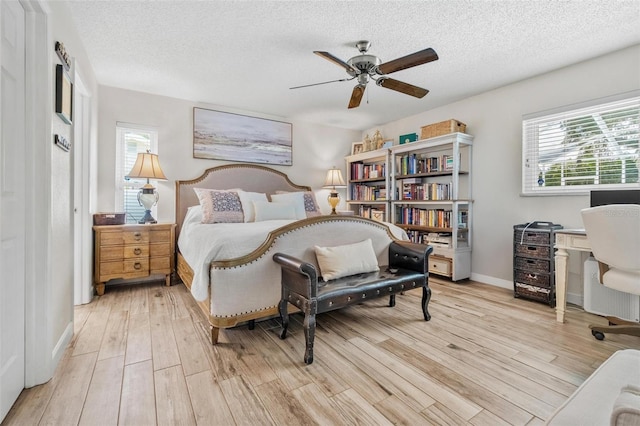 2824 Paddock Dr, Palm Harbor, FL 34684 - bedroom with multiple windows, light wood-type flooring, a textured ceiling, baseboards, and ceiling fan