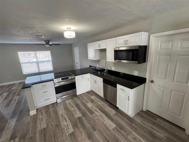 1215 Windsor Cir, Brandon, FL 33510 - kitchen featuring stainless steel appliances, a peninsula, a sink, dark wood-style flooring, and a textured ceiling