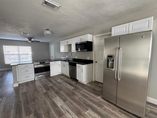 1215 Windsor Cir, Brandon, FL 33510 - kitchen featuring appliances with stainless steel finishes, a peninsula, a sink, a textured ceiling, and white cabinets